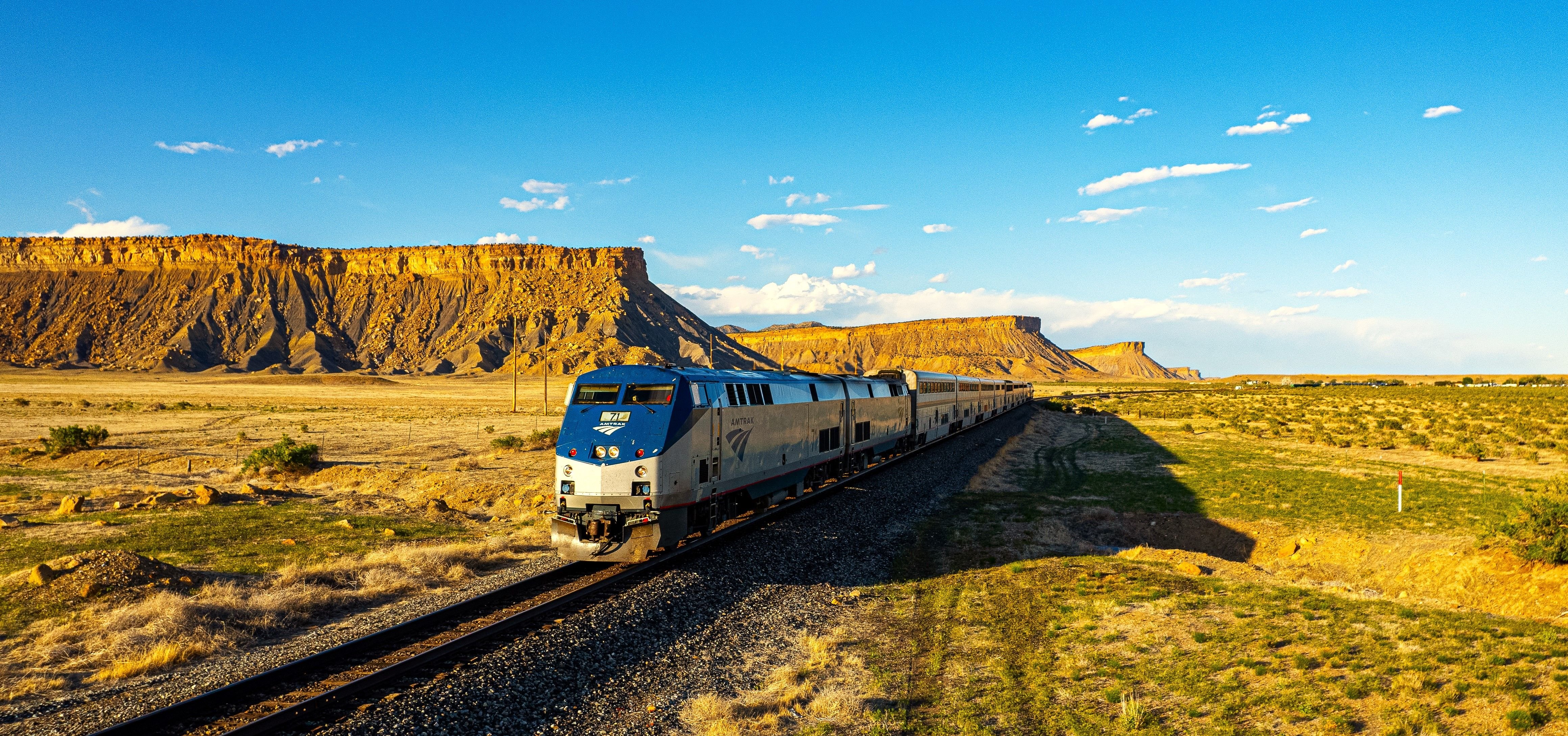 California Zephyr train passing through Colorado's Rocky Mountains with snow-capped peaks in background