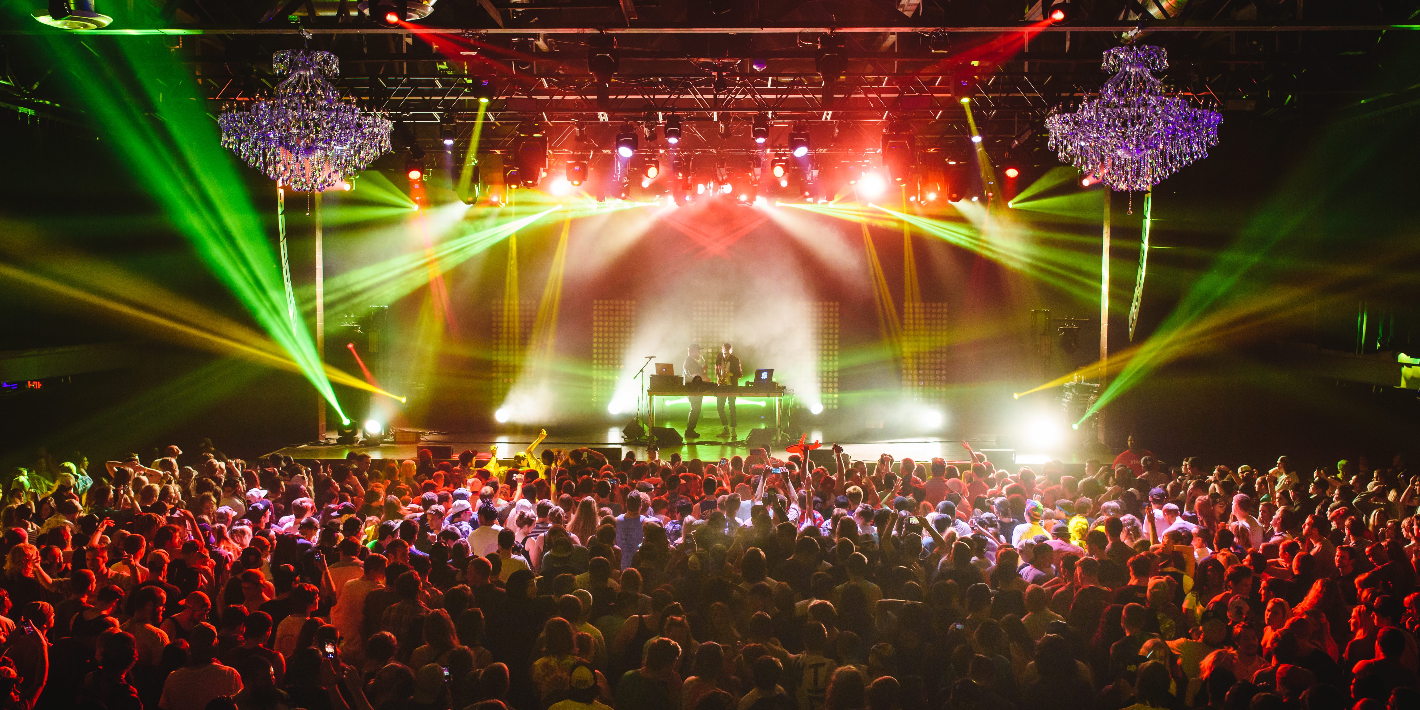 Crowded concert venue with colorful stage lights and enthusiastic audience