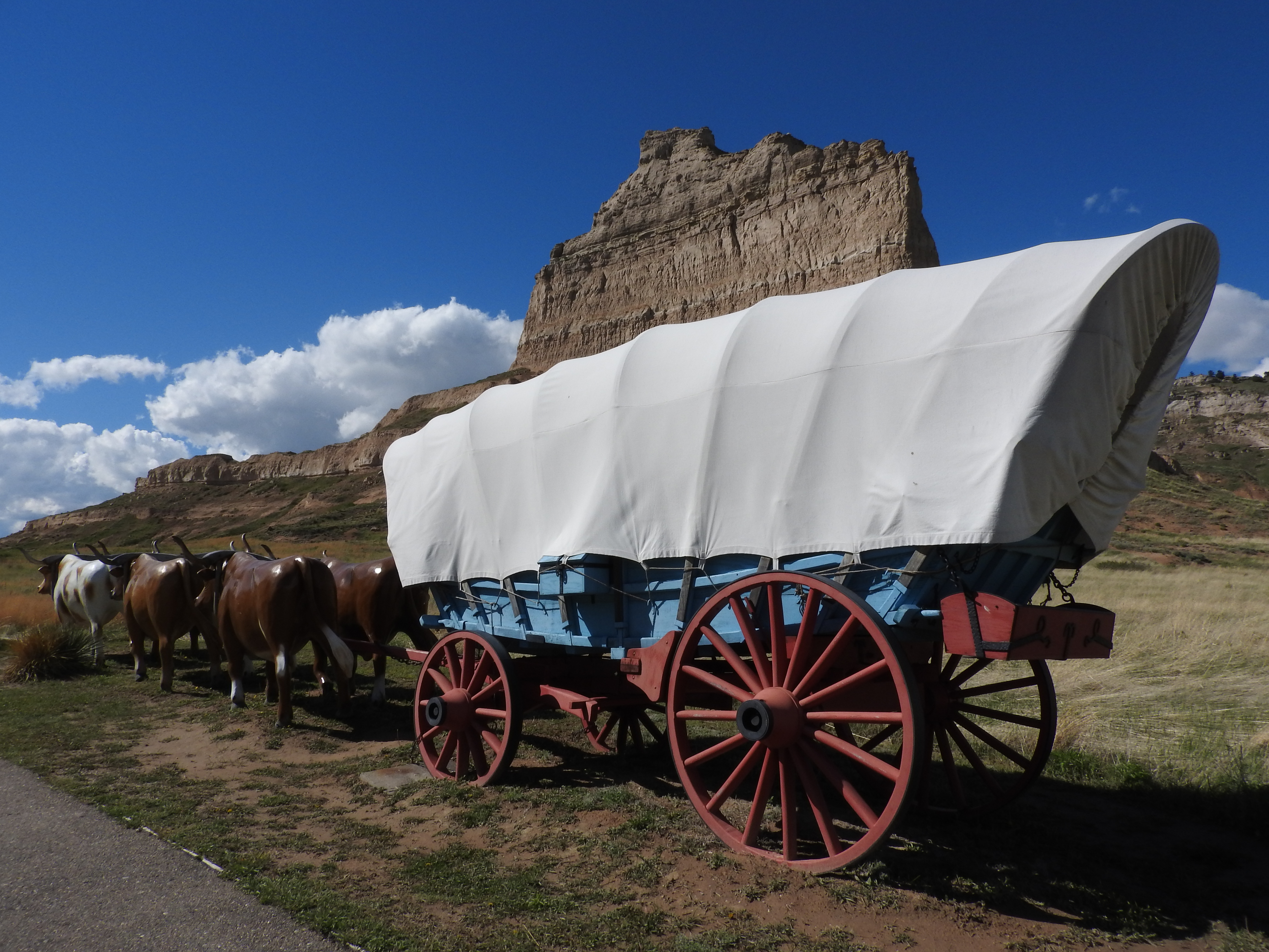 Painting of covered wagons traveling along the Oregon Trail with pioneers