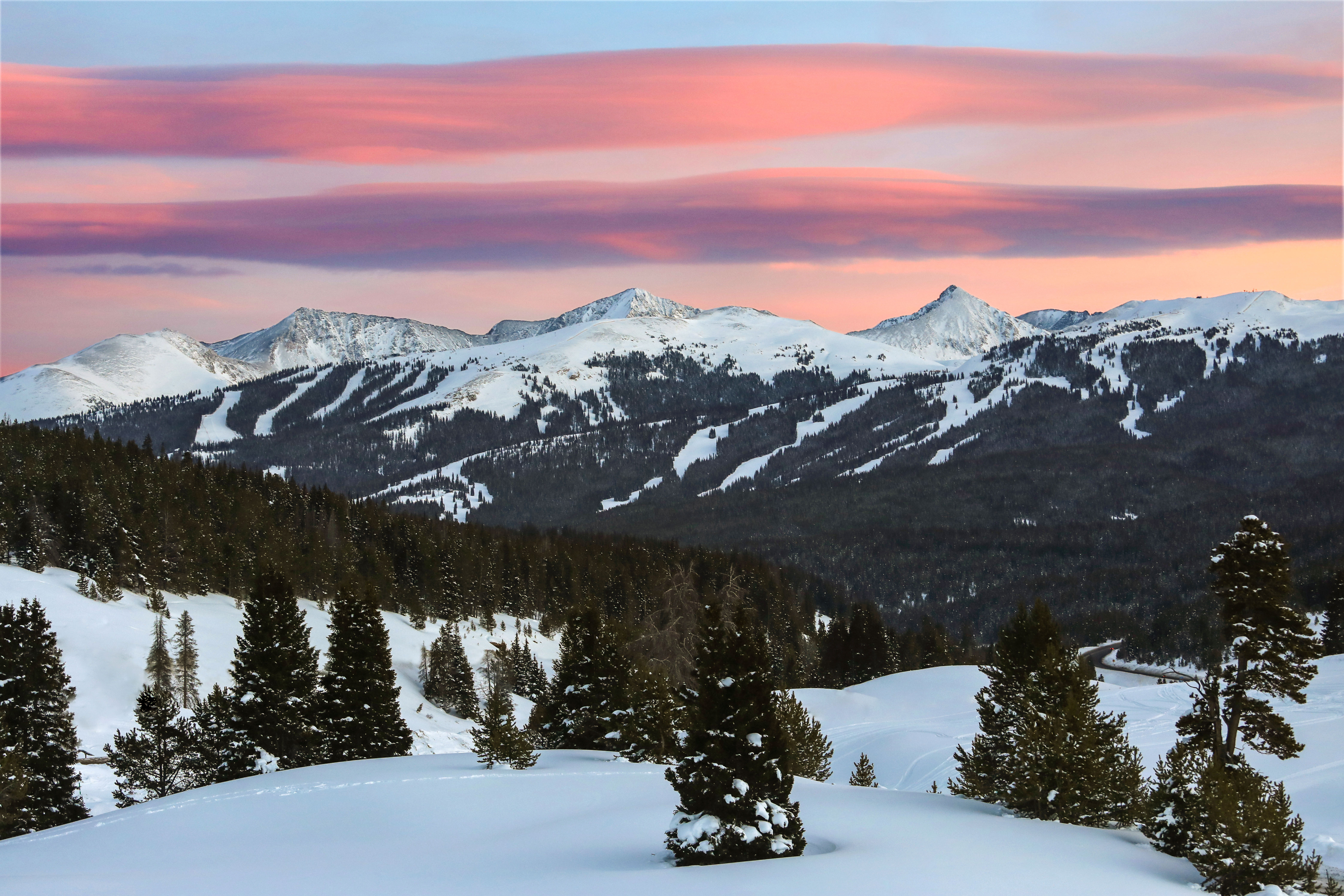 Panoramic view of snow-covered mountains at a Colorado ski resort with skiers descending slopes