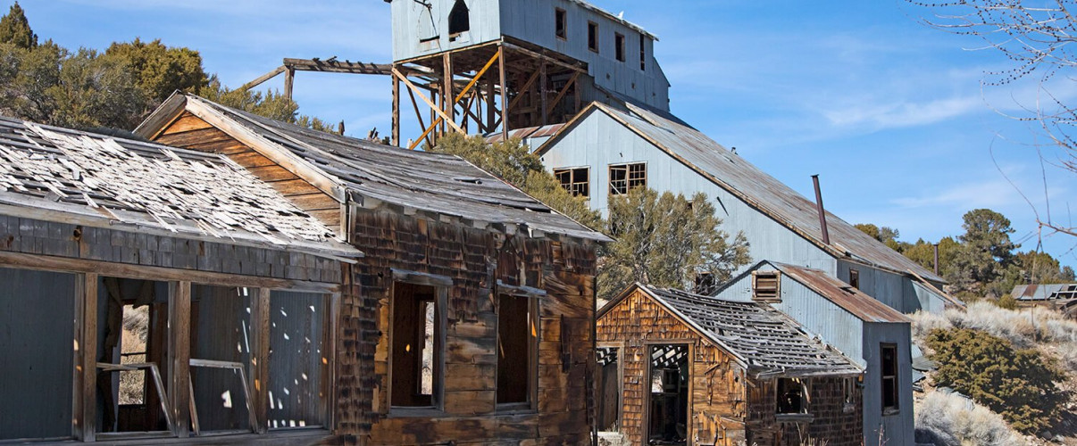 Abandoned wooden structures and mining equipment in a Nevada ghost town set against desert landscape