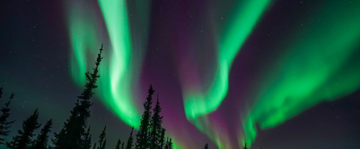 Green aurora borealis dancing over Alaskan mountains at night