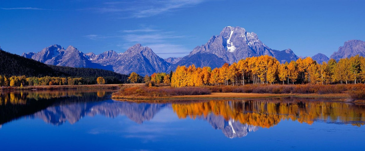 Grand Teton National Park reflection Snow-capped Grand Teton mountains reflecting in calm lake at sunrise
