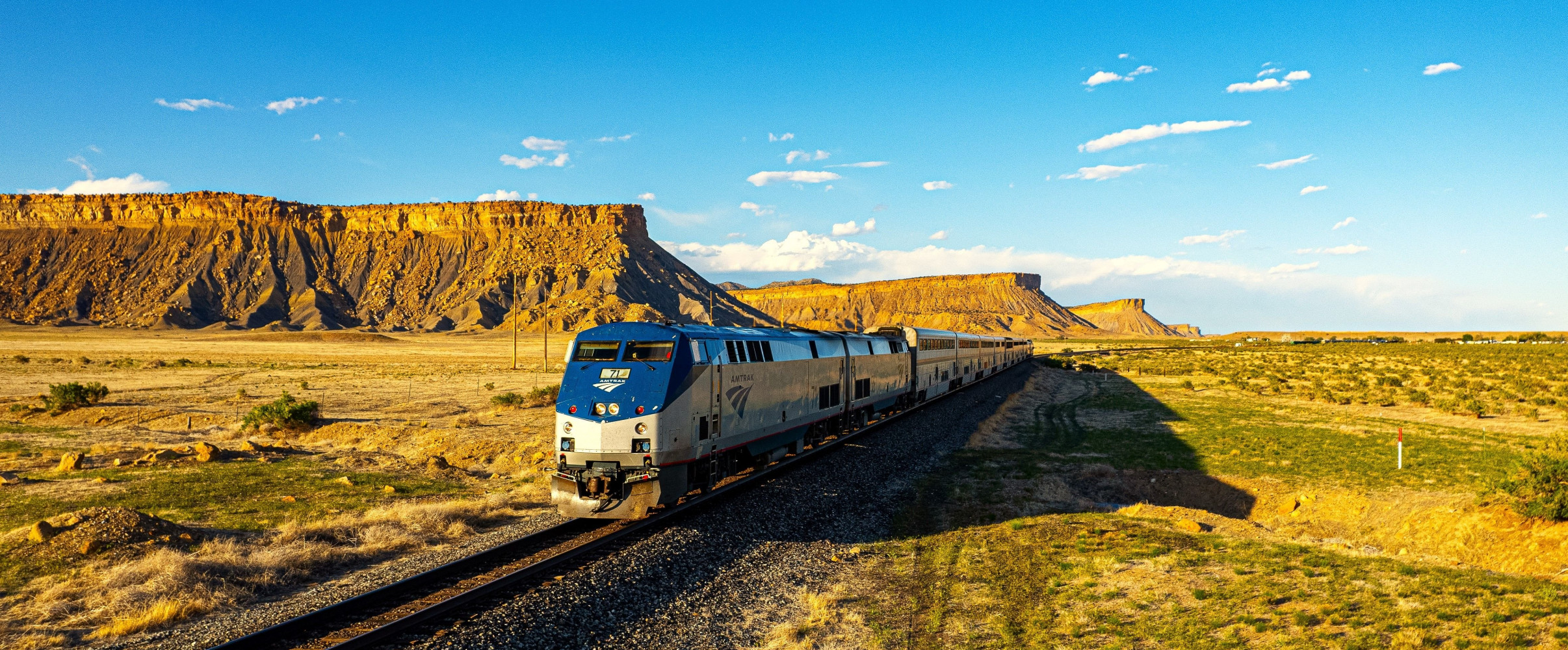California Zephyr train passing through Colorado's Rocky Mountains with snow-capped peaks in background