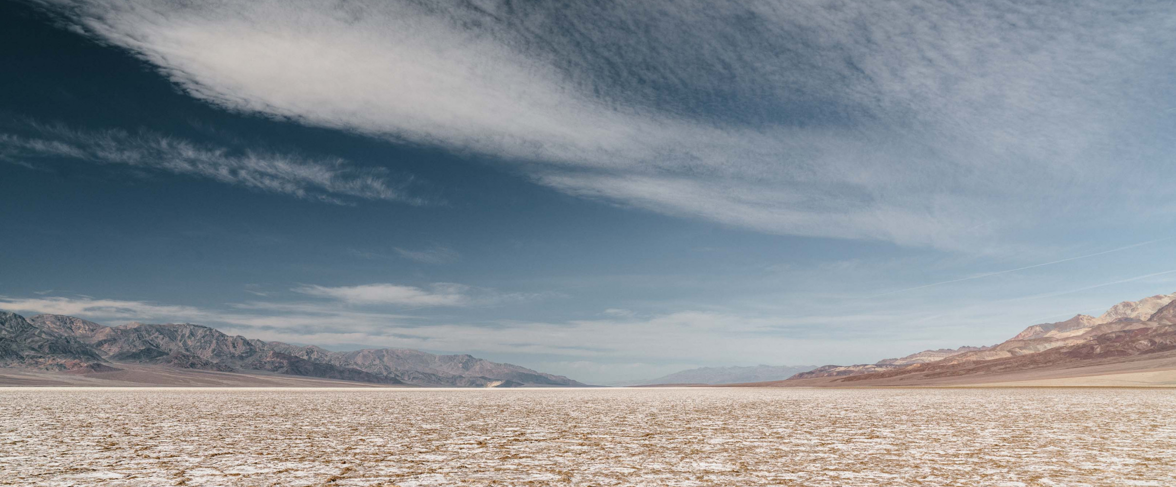 Cracked earth and sand dunes in Death Valley National Park, America's driest location