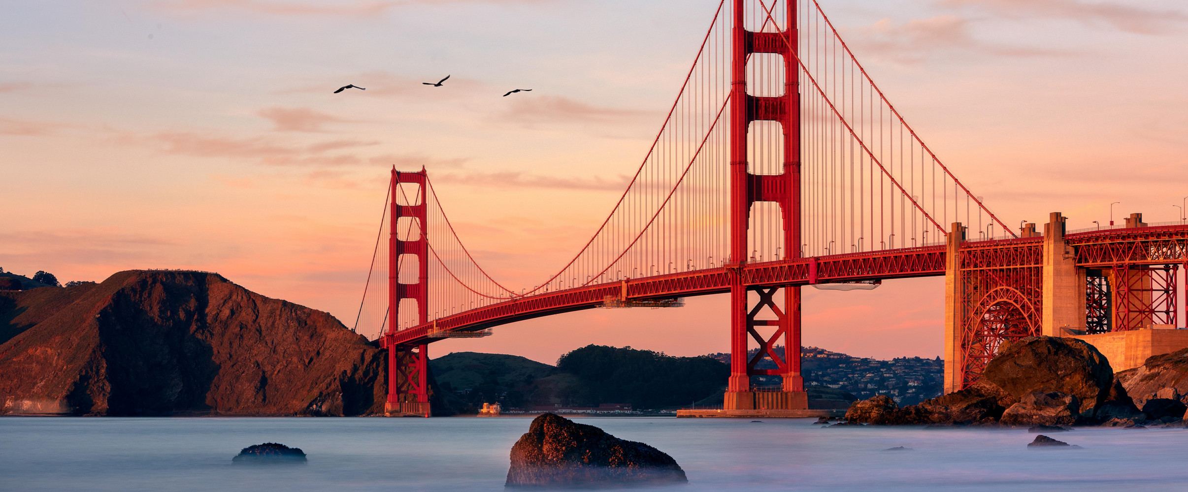 Golden Gate Bridge sunset Golden Gate Bridge glowing orange at sunset with San Francisco skyline in background