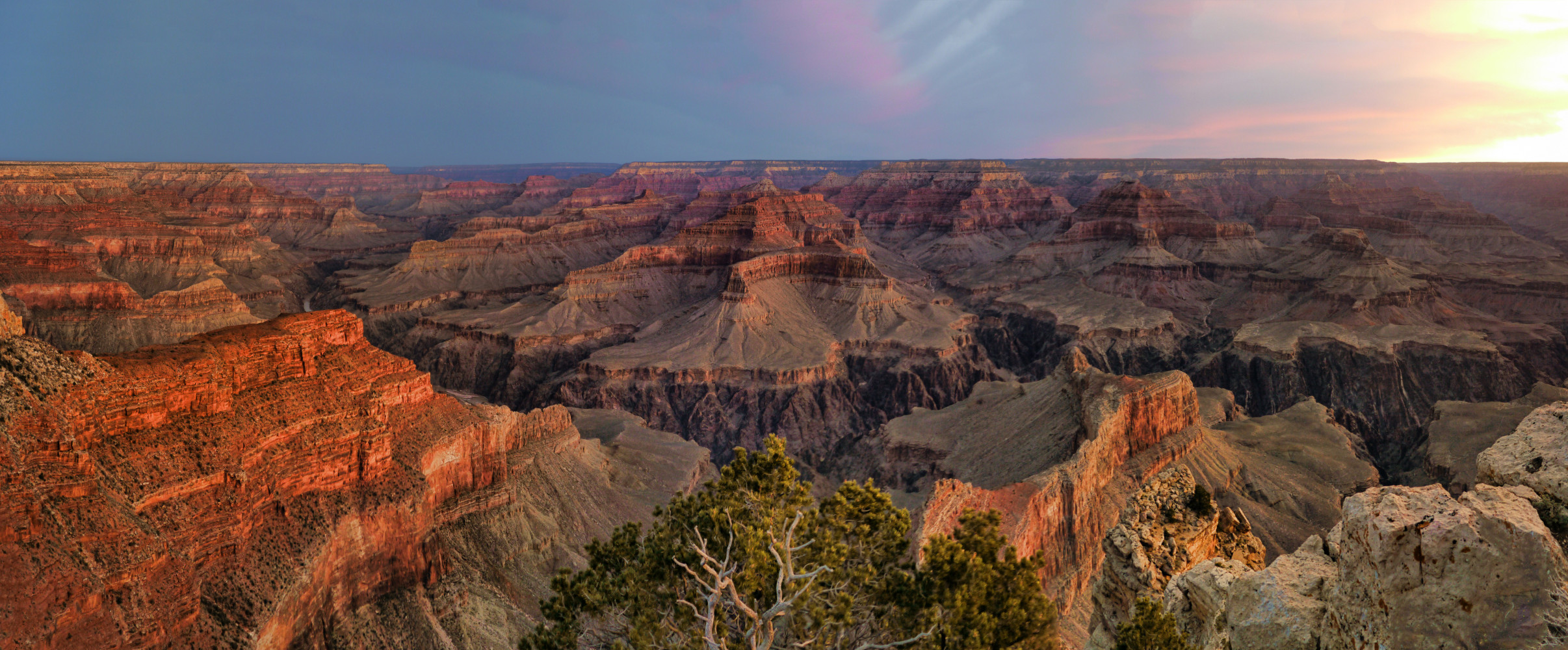 Stunning panoramic view of the Grand Canyon at sunset with dramatic red and orange rock formations