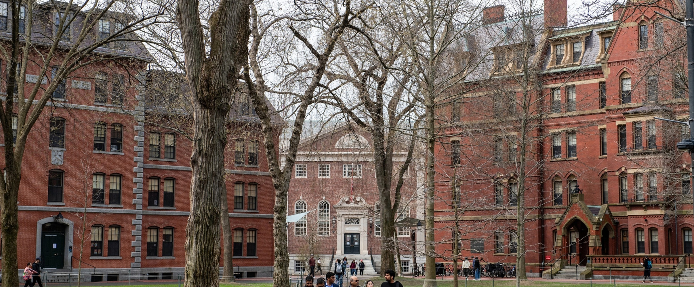 Harvard University's iconic red brick buildings with students walking through Harvard Yard
