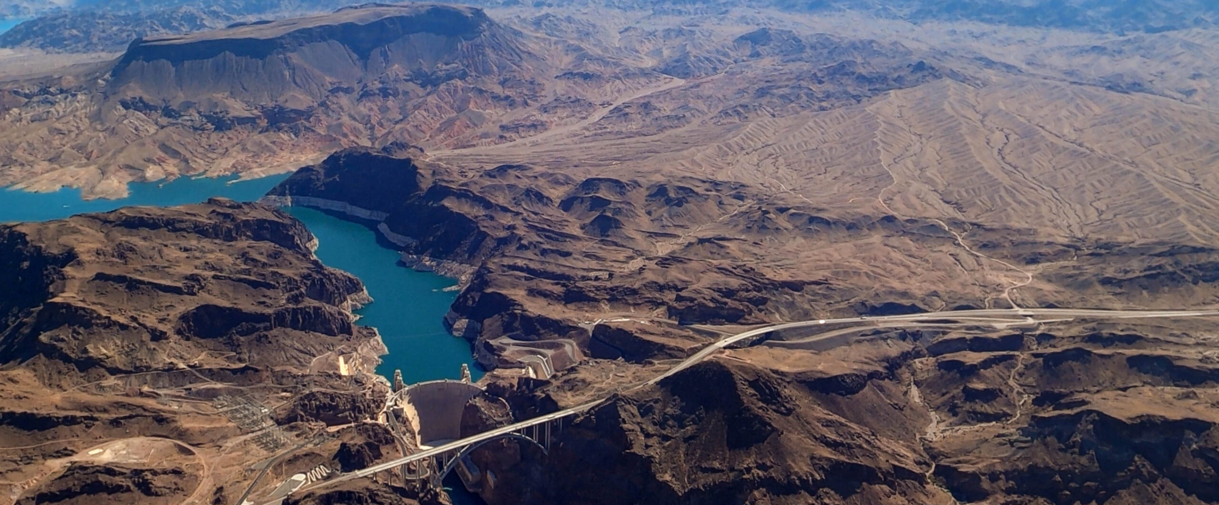 Aerial view of Hoover Dam spanning Black Canyon with Lake Mead reservoir