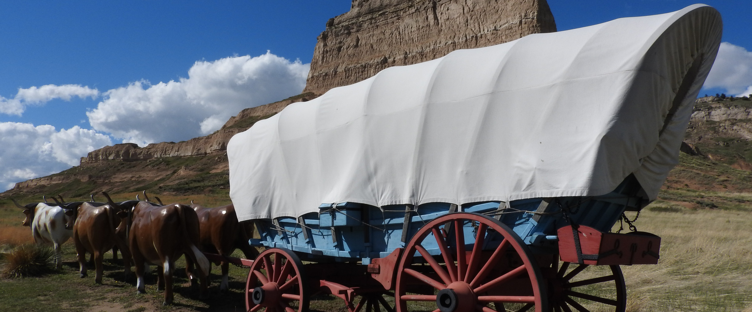 Painting of covered wagons traveling along the Oregon Trail with pioneers