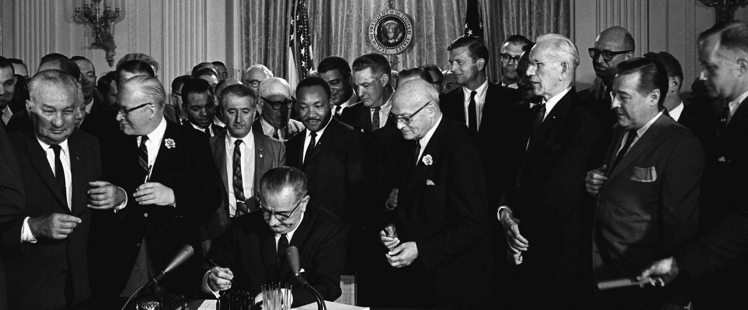 President Lyndon B. Johnson signing the Civil Rights Act of 1964 with Martin Luther King Jr. and other civil rights leaders present