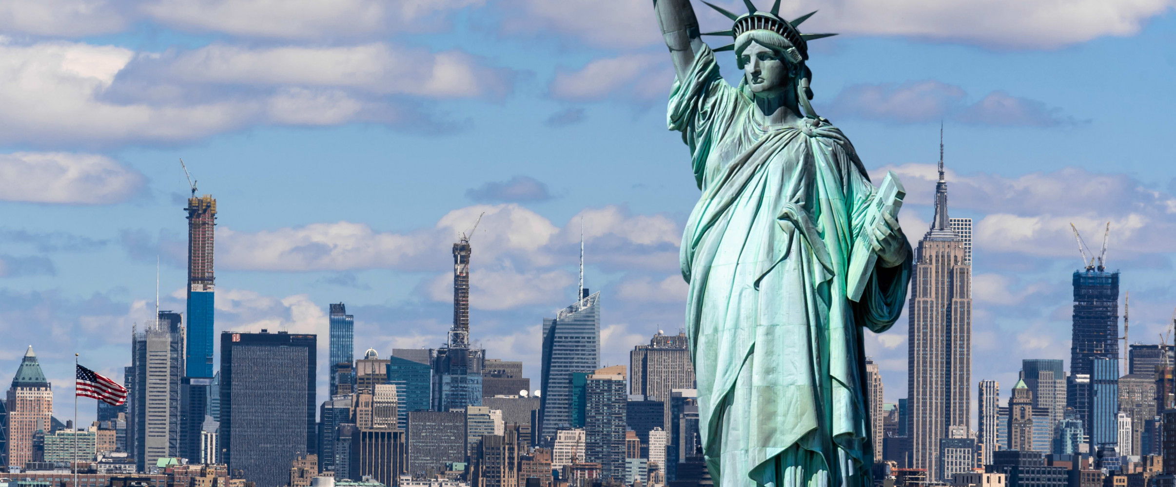 Statue of Liberty standing tall in New York Harbor with Manhattan skyline in background