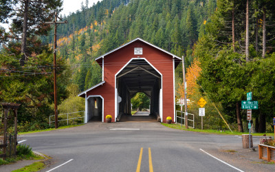 Red wooden covered bridge spanning a river surrounded by autumn foliage