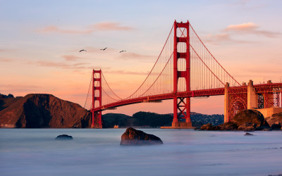 Golden Gate Bridge glowing orange at sunset with San Francisco skyline in background