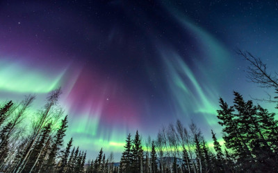 Green aurora borealis dancing over Alaskan mountains at night