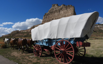 Painting of covered wagons traveling along the Oregon Trail with pioneers
