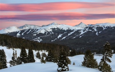 Panoramic view of snow-covered mountains at a Colorado ski resort with skiers descending slopes