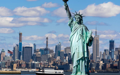 Statue of Liberty standing tall in New York Harbor with Manhattan skyline in background