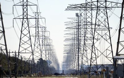High voltage transmission lines crossing the Texas landscape with a sunset in the background