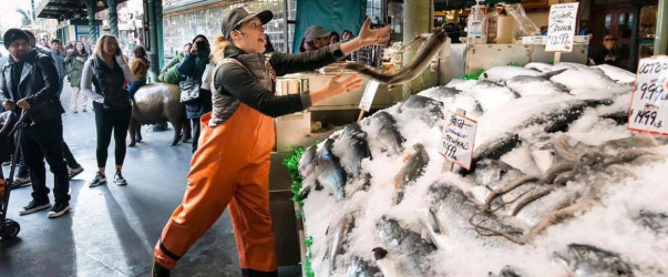Fishmongers tossing fresh fish at Pike Place Market in Seattle