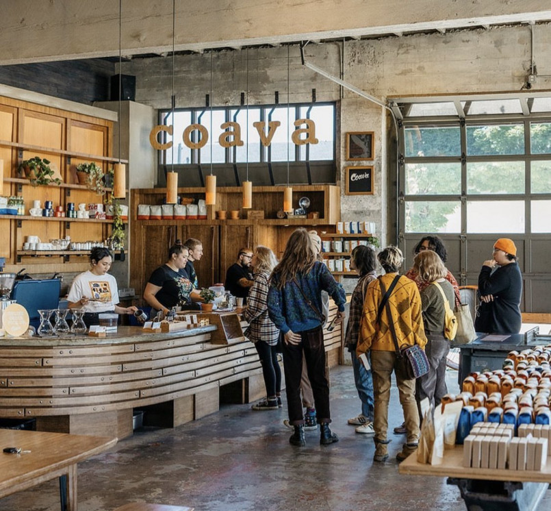 Interior of a vibrant Portland coffee shop featuring wooden beams, lush plants, and patrons enjoying artisanal coffee.