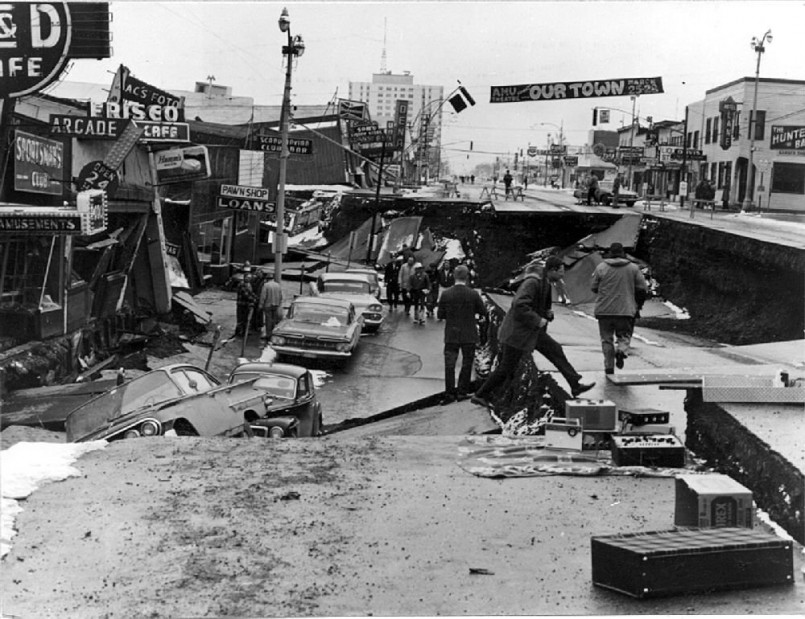 Black and white photograph showing extensive damage to buildings and streets in Anchorage after the 1964 earthquake