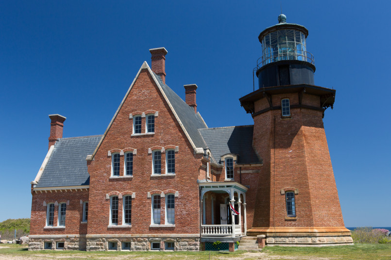 Red brick Southeast Lighthouse perched on Mohegan Bluffs with Atlantic Ocean views