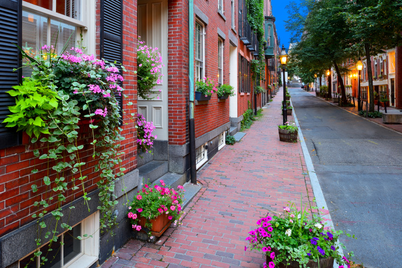 Historic brick row houses with black shutters on a cobblestone street in Boston's Beacon Hill neighborhood