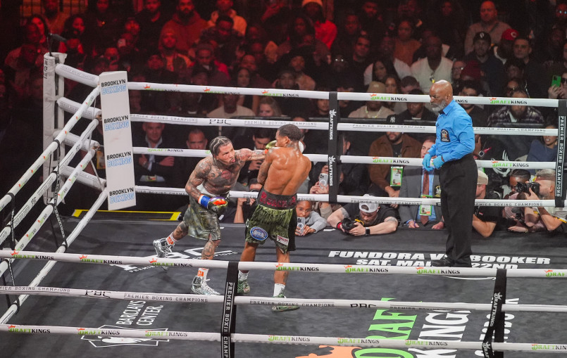 Two professional boxers facing off in a championship fight with a large crowd