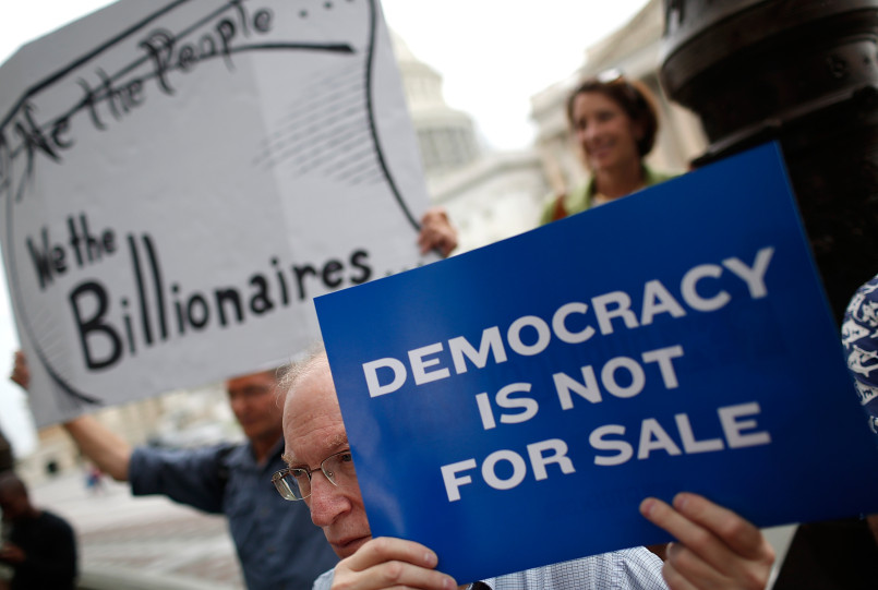 Protesters holding signs about money in politics and campaign finance reform