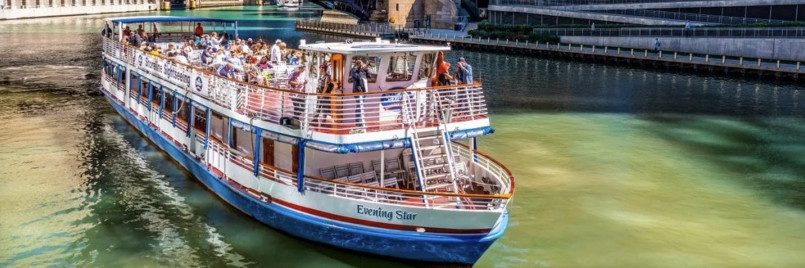 Tour boat on Chicago River surrounded by skyscrapers including Willis Tower and Trump Tower