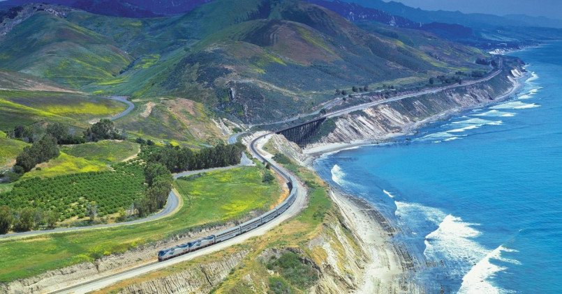 Coast Starlight train traveling along the edge of the Pacific Ocean near Santa Barbara with waves crashing against the shoreline
