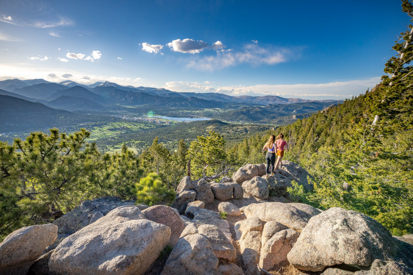 Hikers on a mountain trail surrounded by Colorado's wildflower-covered alpine meadows