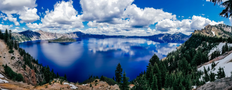 Panoramic view of Crater Lake's intense blue waters with Wizard Island visible within the caldera