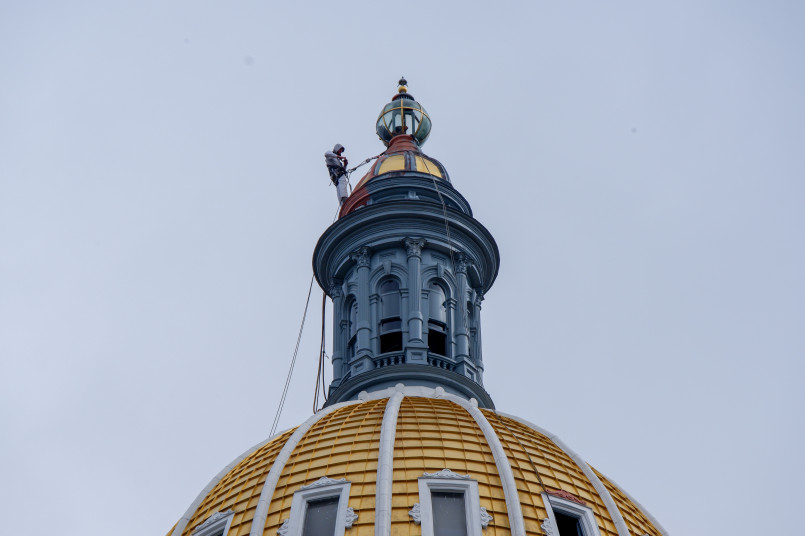The gold-domed Colorado State Capitol building in Denver with Rocky Mountains in background