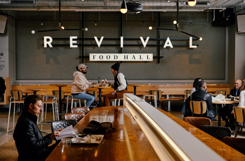 Diners enjoying meals at various vendors in the stylish interior of Revival Food Hall