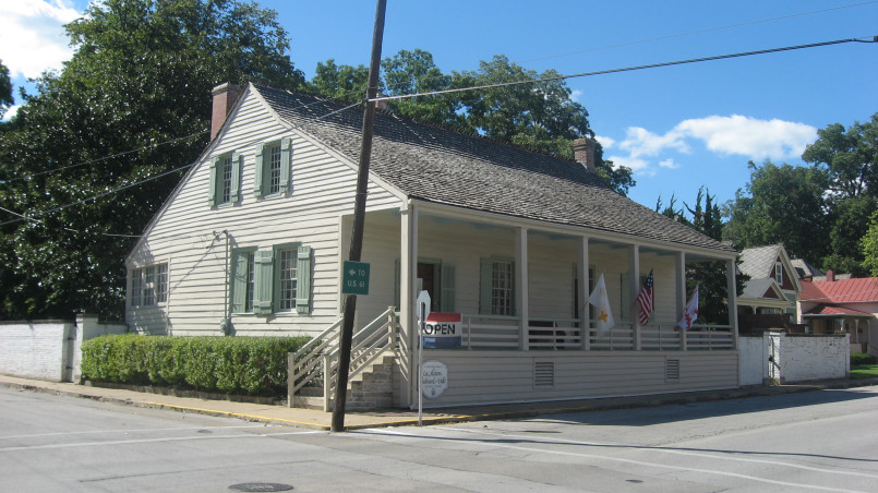 Historic French colonial building with vertical log construction and wide porch gallery