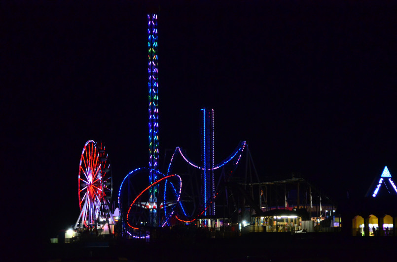 Illuminated Galveston Pleasure Pier extending into Gulf of Mexico at twilight with colorful lights