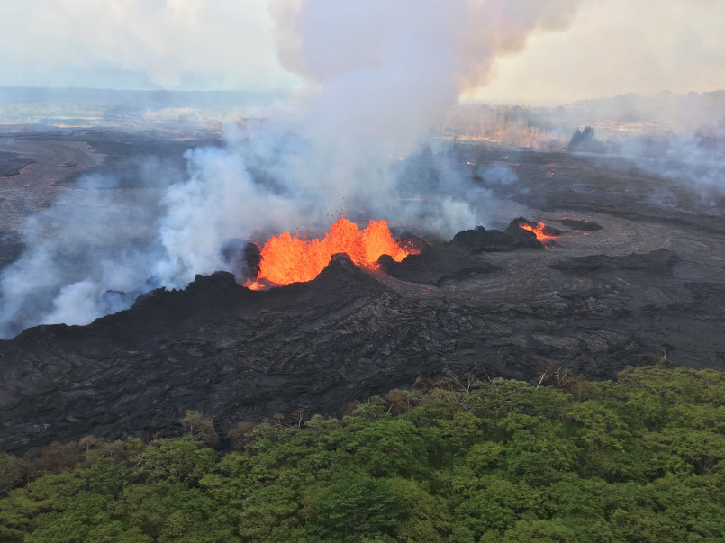 Dramatic red lava flow from Kilauea volcano at night against dark landscape