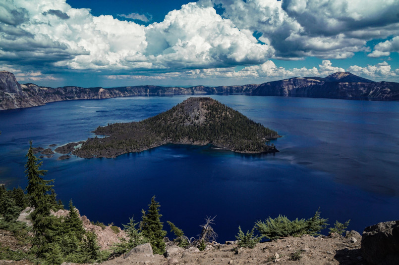 Hikers on rim trail with views of deep blue Crater Lake and Wizard Island