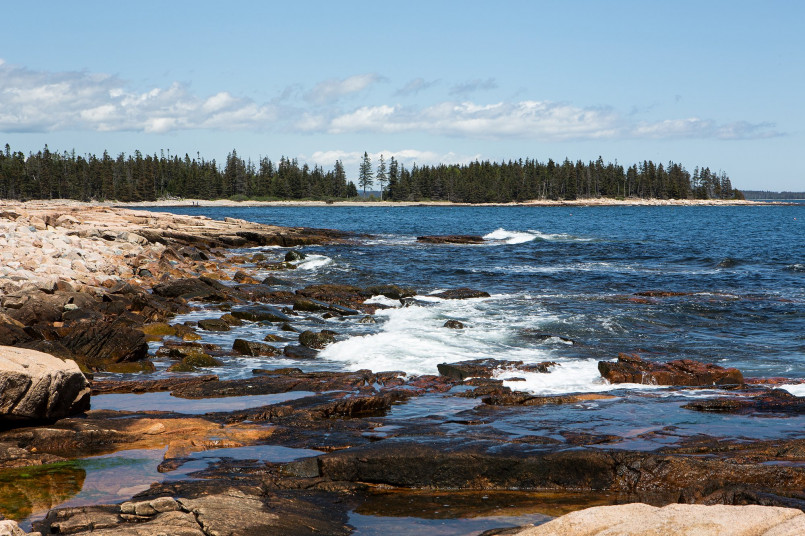 Hikers on rocky coastal trail with Atlantic Ocean views in Acadia National Park