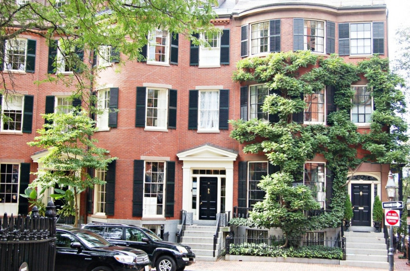 Historic brownstone buildings with gas lamps on a cobblestone street in Beacon Hill, Boston