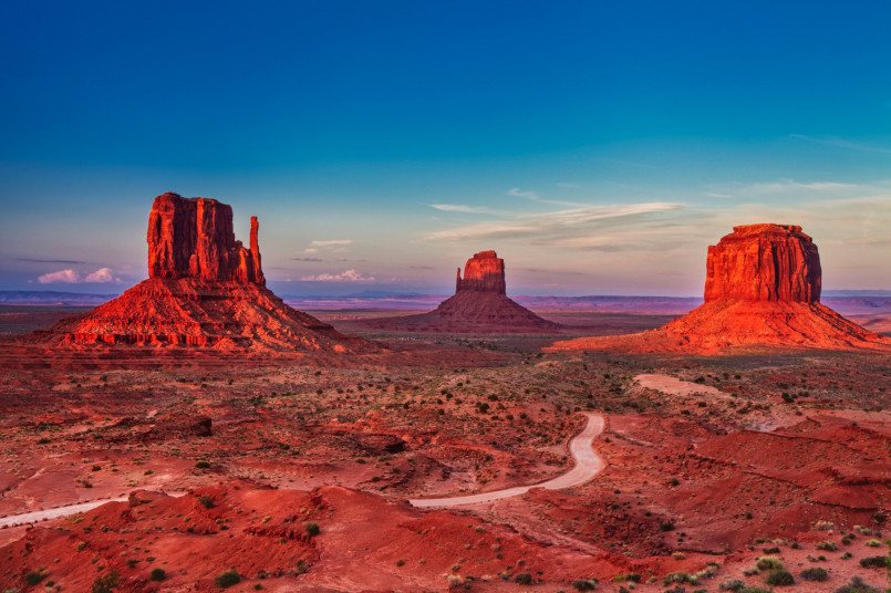 Iconic red sandstone buttes of Monument Valley silhouetted against a dramatic sunset sky