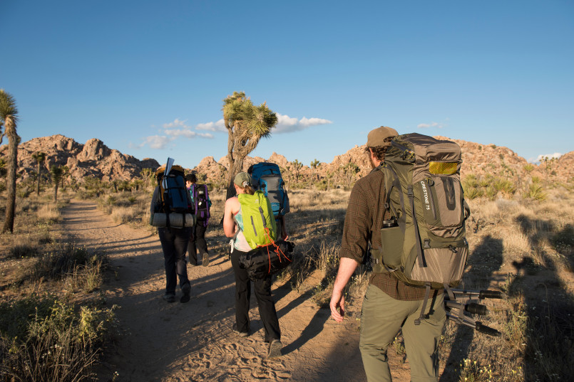 Joshua Tree National Park desert hiking trail Hikers on trail among boulder formations and Joshua trees in Joshua Tree National Park
