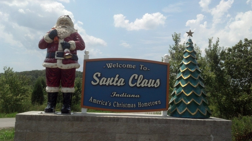 Large festive welcome sign to Santa Claus, Indiana featuring Santa Claus himself