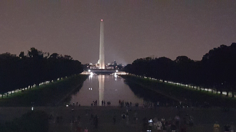 Lincoln Memorial illuminated at night with reflection in the pool and Washington Monument in distance