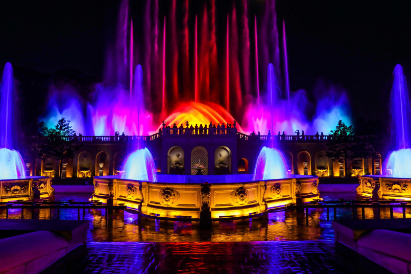 Illuminated fountain display with colorful water jets at dusk