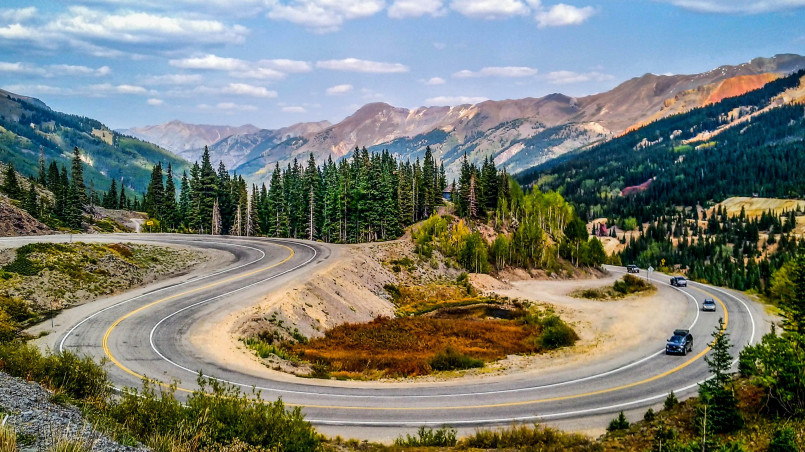 Narrow winding road of the Million Dollar Highway with steep cliffs and mountain views
