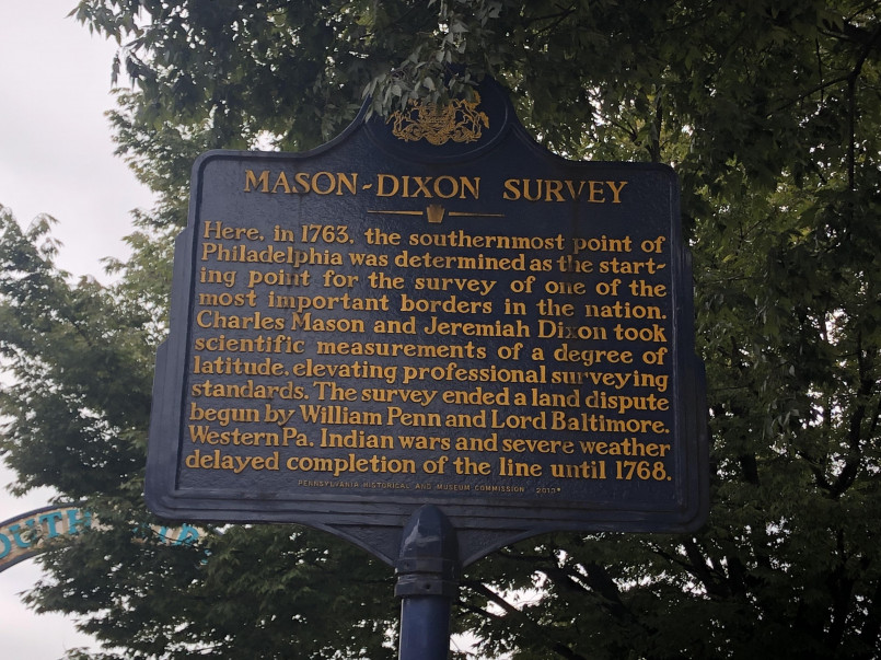 Modern mason dixon line marker with tourists Modern tourists visiting a Mason-Dixon Line marker along the Pennsylvania-Maryland border
