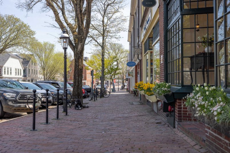 Cobblestone street lined with shops and cedar-shingled buildings with flower boxes in downtown Nantucket